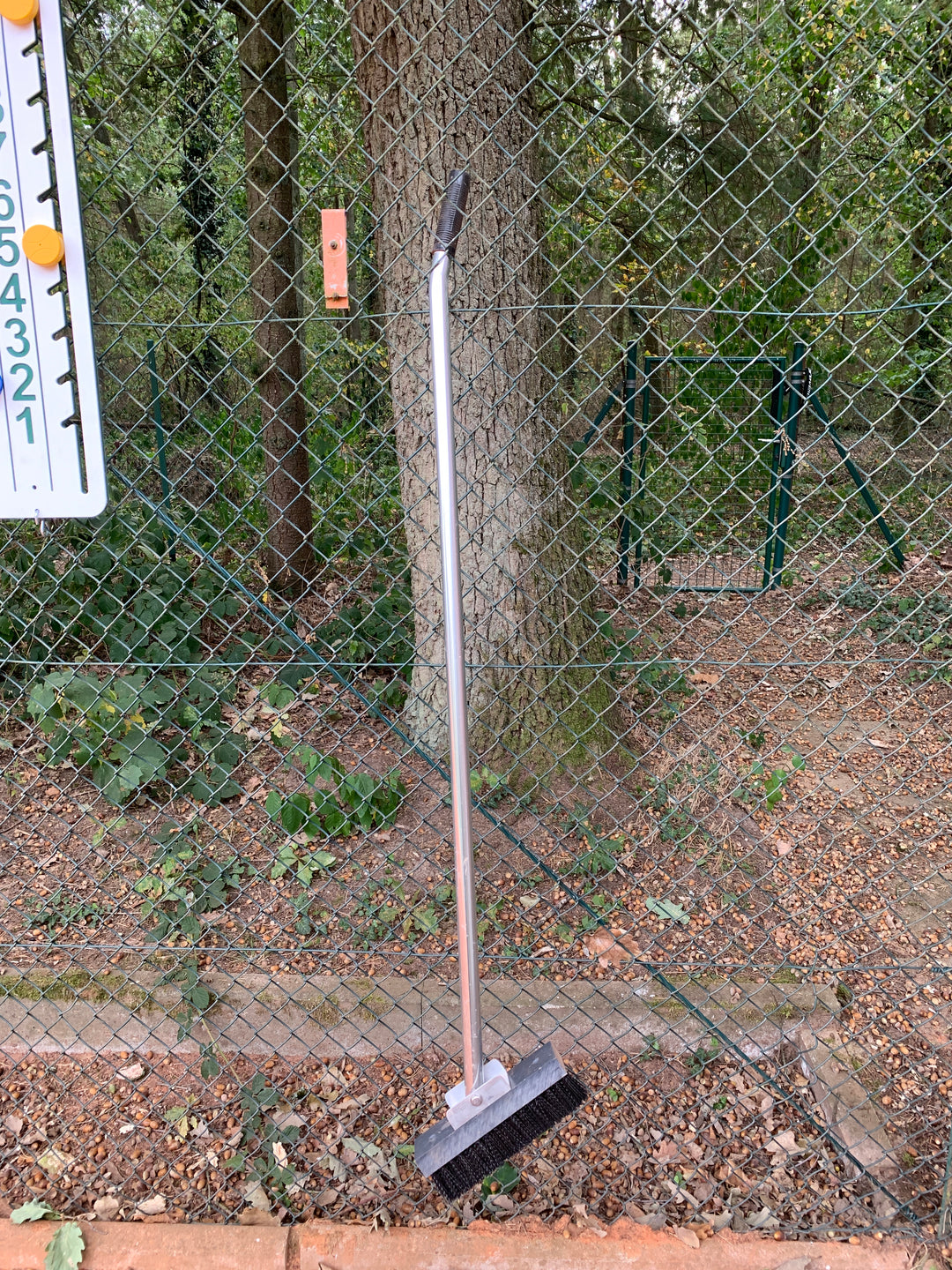 Linienbürste mit Gelenk sauber im Zaun aufgehängt.